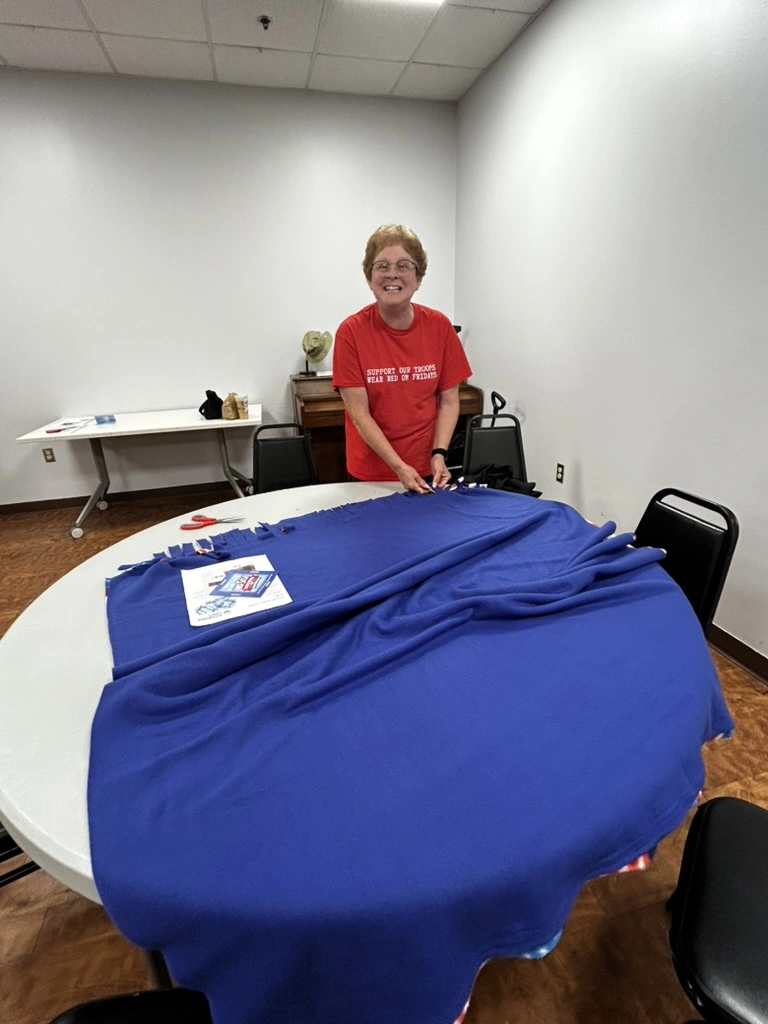 Volunteer tying fringe on a blue no-sew fleece blanket at the BV Mall Senior Center